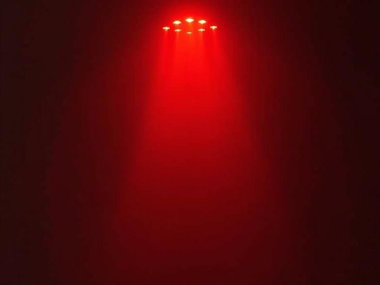 A beam of red light shines in a dark space. The light creates a dramatic atmosphere with surrounding darkness.