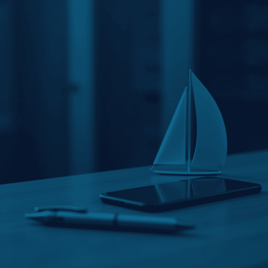 A monochromatic image of a smartphone, pen, and sailboat model on a desk.