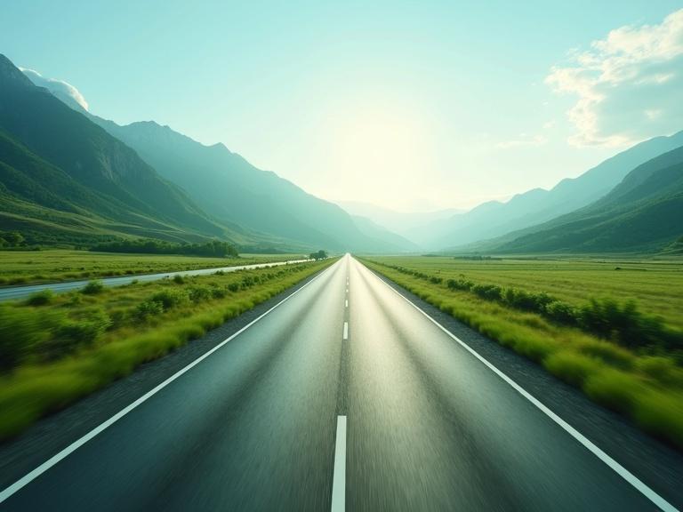 Green valley landscape features a straight highway. Highway has two lanes. Area is surrounded by mountains. Image conveys a sense of speed.
