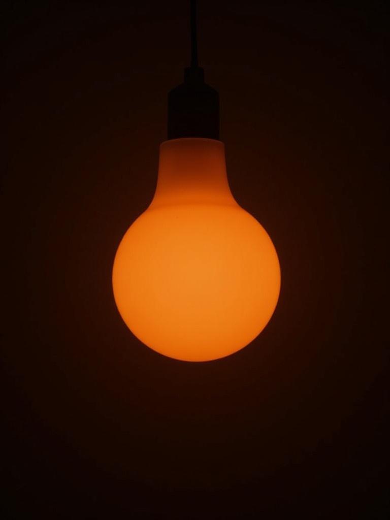 Image shows light from a sunset lamp. Warm glow against dark background. Simple and elegant lighting ambience.