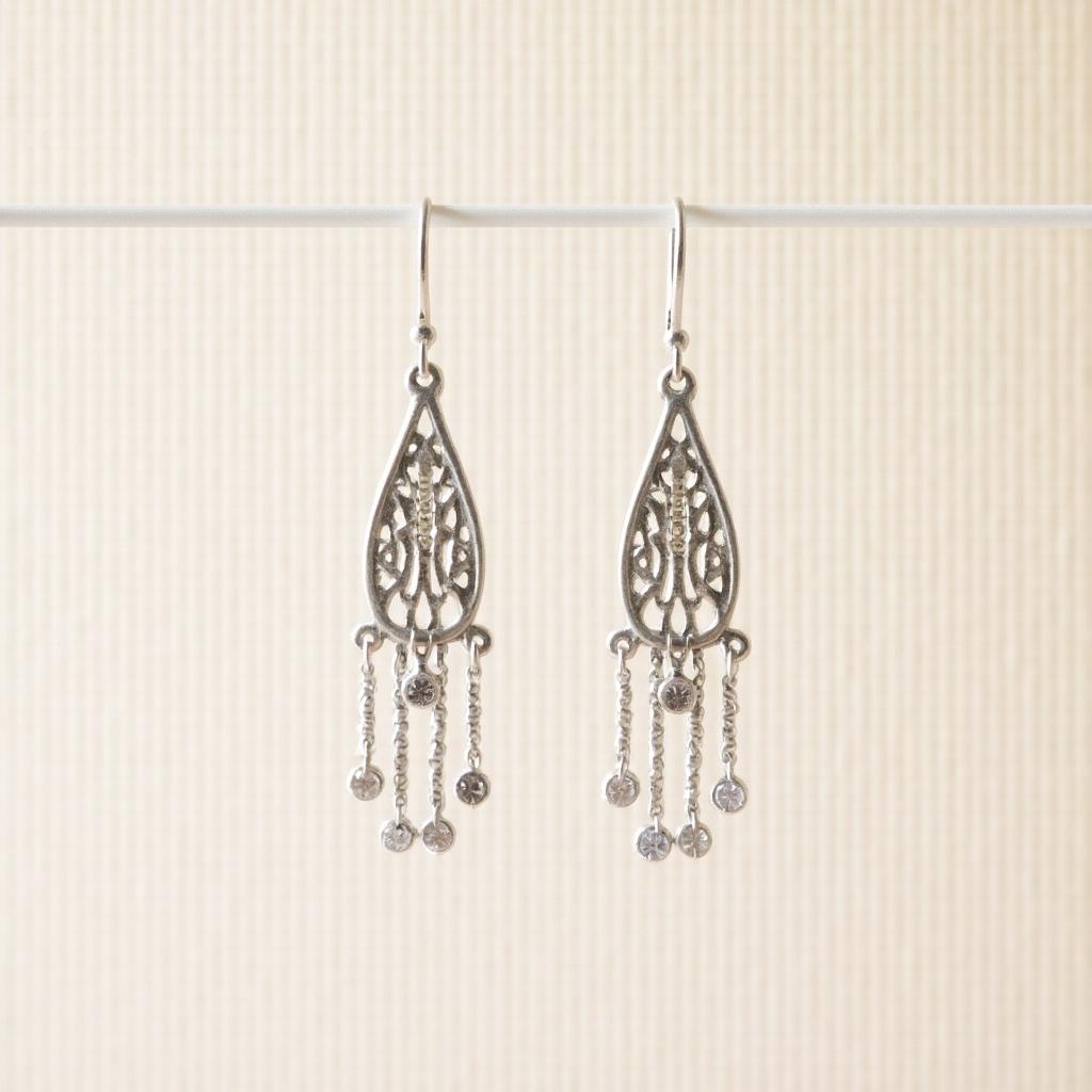 Close-up image of silver dangle earrings. Intricate design with hanging elements. Earrings showcase fine craftsmanship.