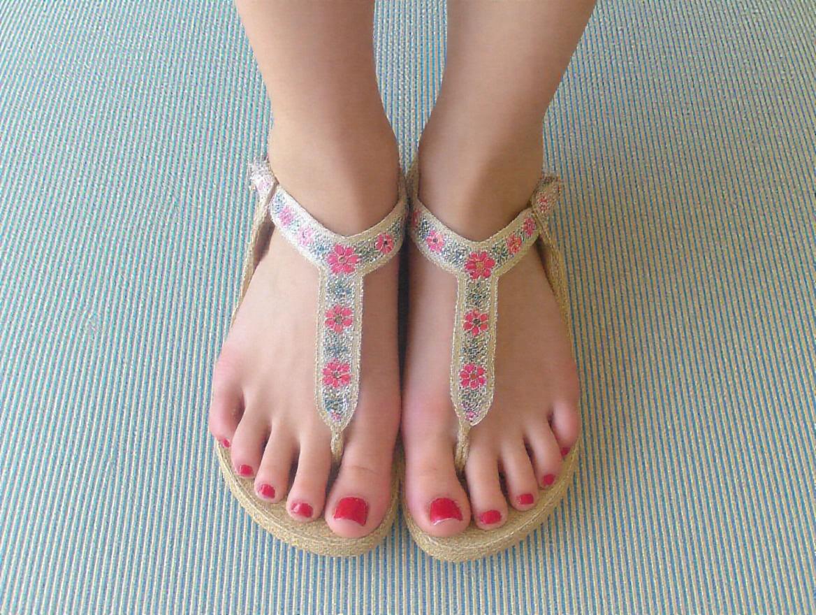 Little pretty feet wearing decorative sandals on a stylish surface