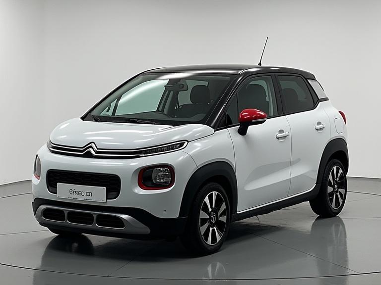 CITROEN C1, showcasing modern design with a white body, black roof, and red accents, displayed in a showroom setting.