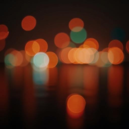 Image features a bokeh effect with orbs of softly blurred lights in various colors. The scene is dark with highlights of orange, blue, and green. It conveys a sense of depth and ambiance.
