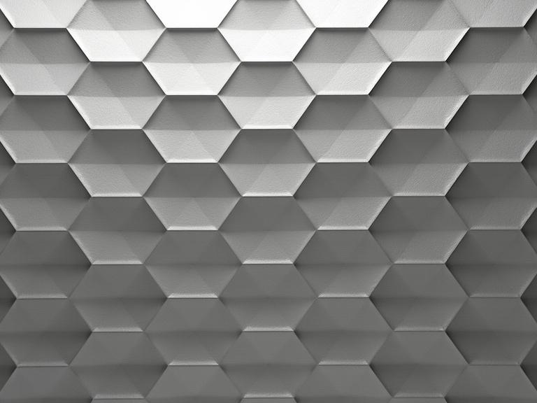 Geometric patterned wall with repeating 3D textured hexagons in metallic gray. Deep subtle shadows in the recessed hexagon shapes create depth. Surface displays a brushed or hammered metallic texture. Strong, sharp lines and precise angles characterize the design. Color palette is monochromatic gray tones from light to dark. Emphasizing a clean, precise geometric design. Full front-facing perspective with even neutral lighting. Calm, serene and sophisticated mood.