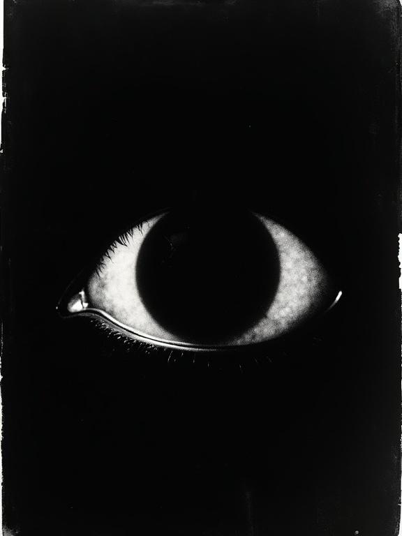 An experimental photo features a large silhouette eye. The eye is filled with a cosmic void against a black background. The film negative shows distortion.
