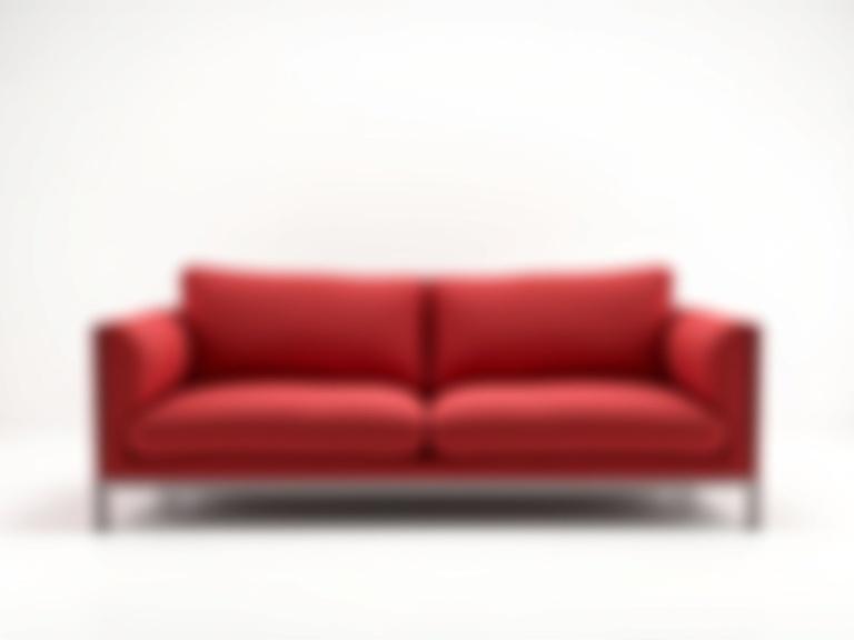 Photorealistic image of a modern luxury couch in bold deep red color. Clean minimalist lines and matte or velvet texture. Placed slightly off-center on pure white background with soft diffused lighting. No other objects in the scene. Elegant minimal high-end composition.