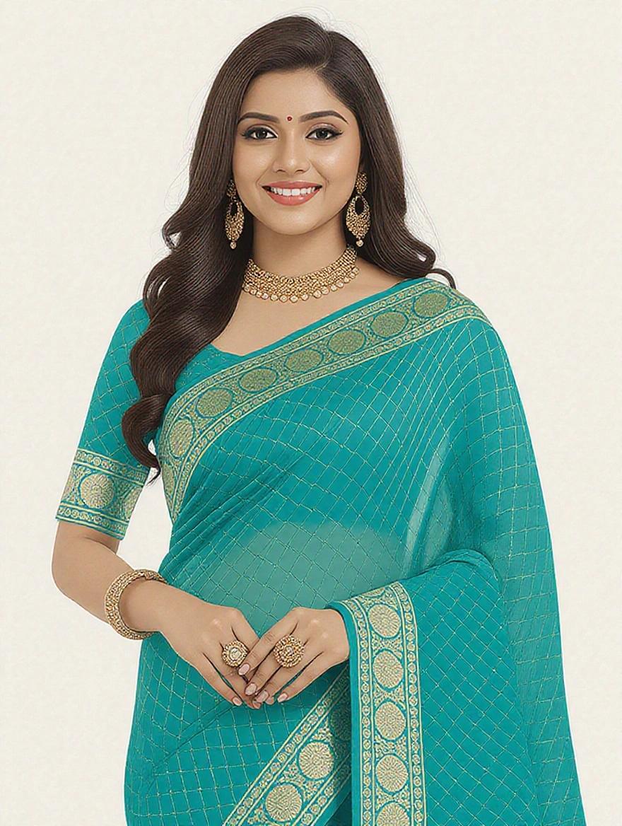A girl stands in a left side view. She wears a blue saree with intricate designs. Joining hands with a smile. Wears necklaces, earrings, and sandals. Soft light highlights outfit details.