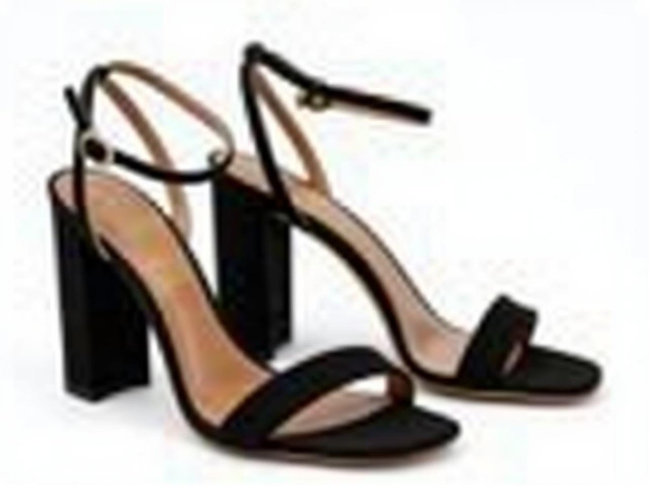 The image shows a pair of stylish high-heeled sandals. They are predominantly black and feature a smooth, suede-like texture. The design includes a slender ankle strap that connects to a thicker heel, which provides both elegance and stability. The front of the sandals has a minimalist strap, giving them a chic and modern look. These shoes would be suitable for various occasions, such as parties or formal events.