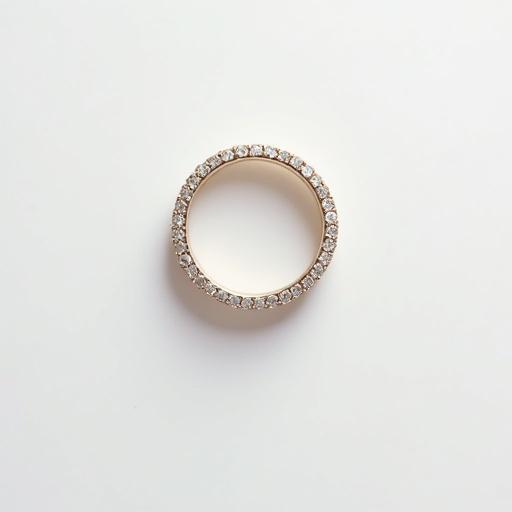 A glamorous wedding ring placed on a white flat surface. The shot is taken from directly above using a DSLR camera. Highlights the ring's design and sparkle. Ideal for product display in a photography studio.