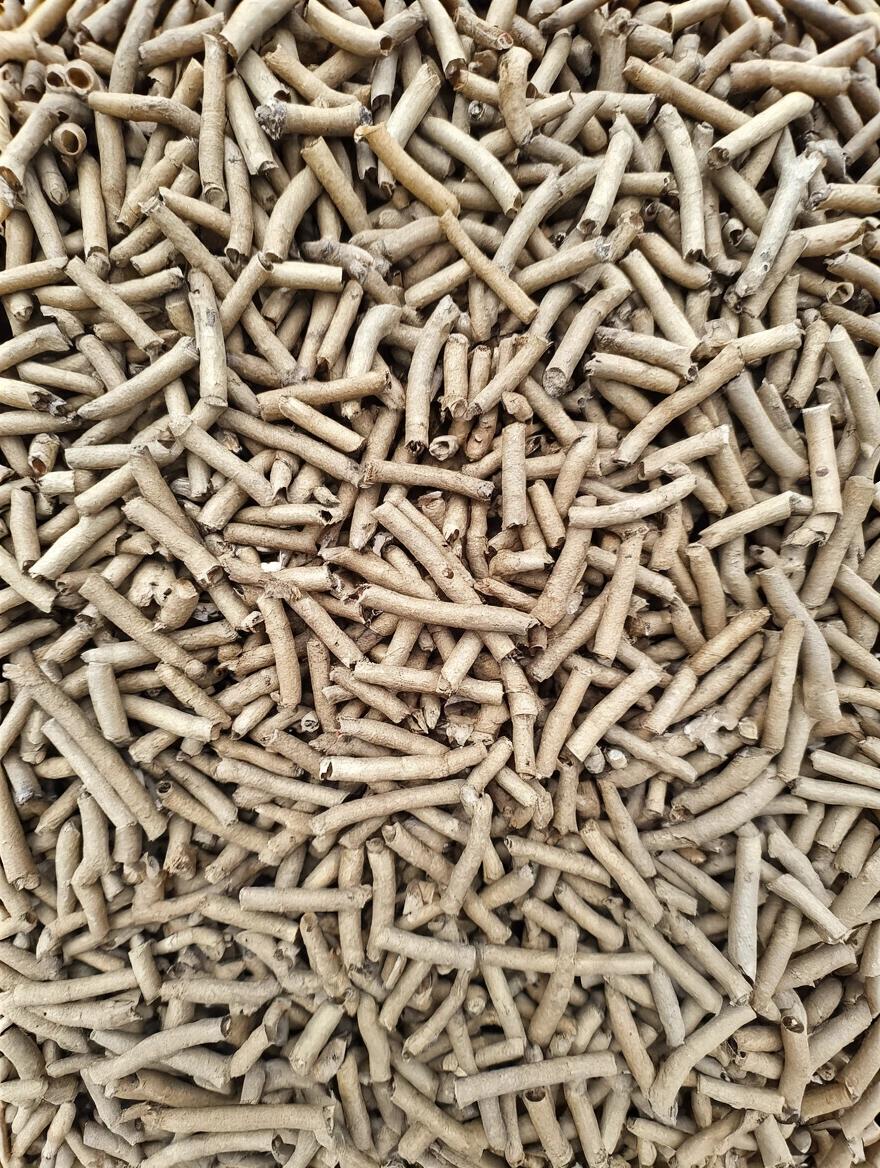 Densely packed cylindrical shapes made of natural material. The arrangement shows various lengths and widths of the pieces creating a textured surface. The color is predominantly neutral, reflecting an organic theme.