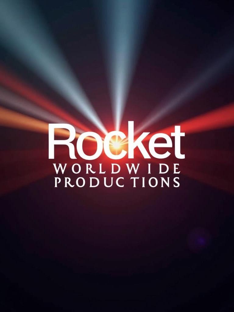 Logo resembles famous film company logo. Text altered to Rocket Worldwide Productions. Background features dramatic colors resembling cinematic atmosphere. Bright beams of light radiate from the logo, enhancing grandeur. Associated with film and media production.