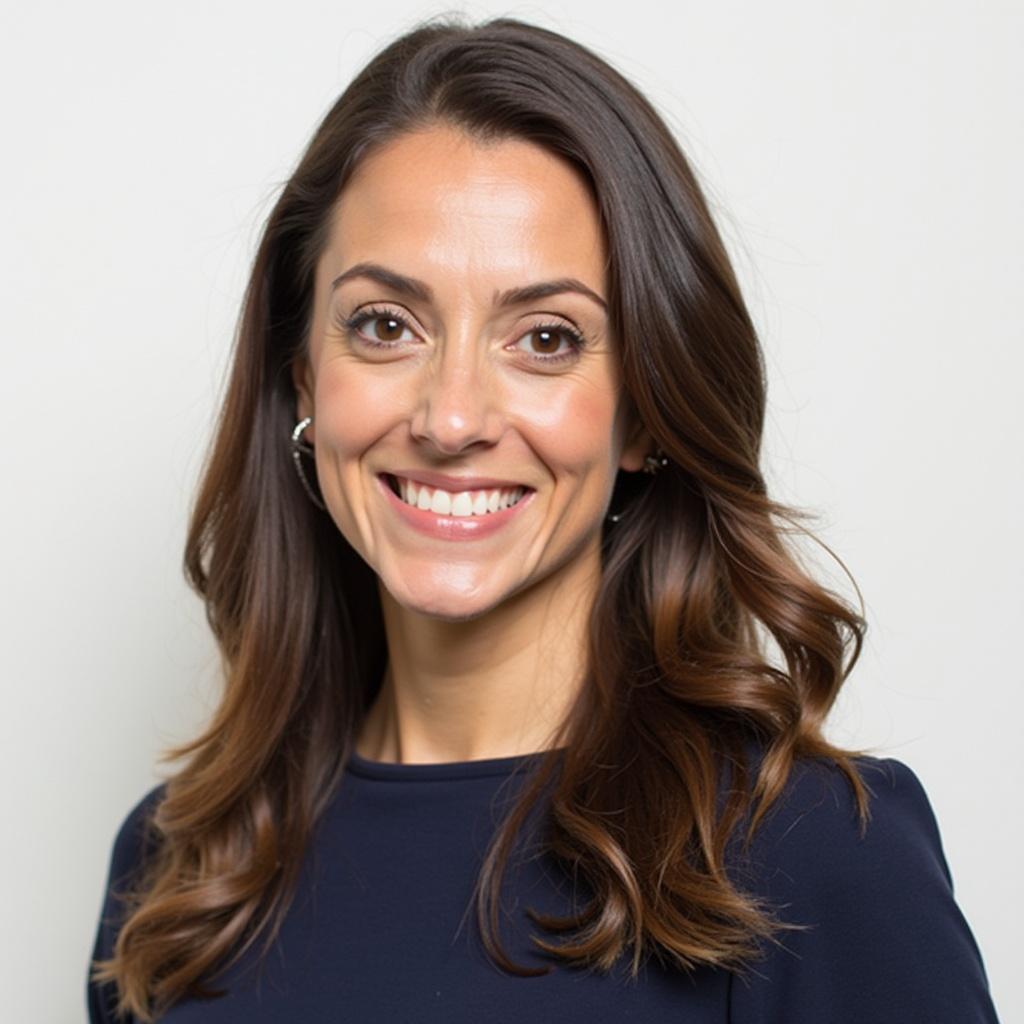 This image features a portrait of a woman with long, flowing brown hair, smiling confidently. She is wearing a navy blue top that complements her warm skin tone. The background is a subtle off-white, adding to the professionalism of the image. The lighting is soft and flattering, enhancing her features. This image is perfect for corporate branding, networking events, or professional social media profiles.