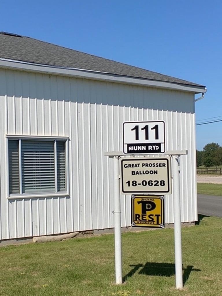 Signage displays event name Great Prosser Balloon Rally Sign includes address 111 Nunn Rd Building located on small airport property