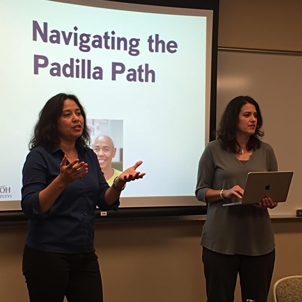 Two women present in a bright classroom. One gestures while the other holds a laptop. The presentation is titled 'Navigating the Padilla Path'.