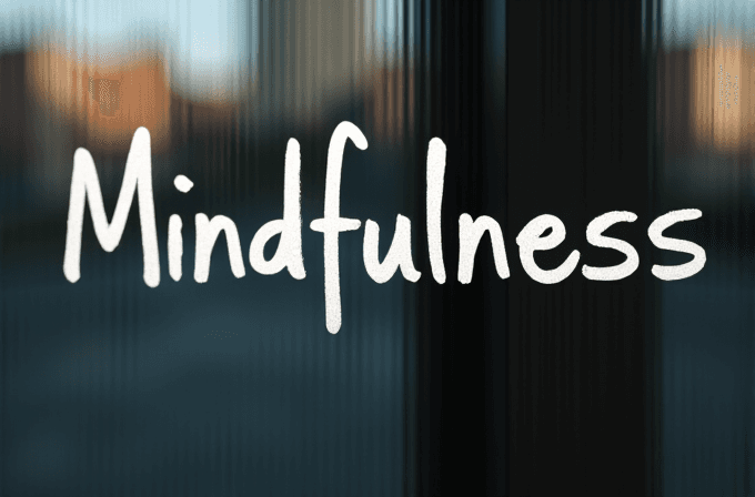 The word 'Mindfulness' is written in white on a blurred, calming background.