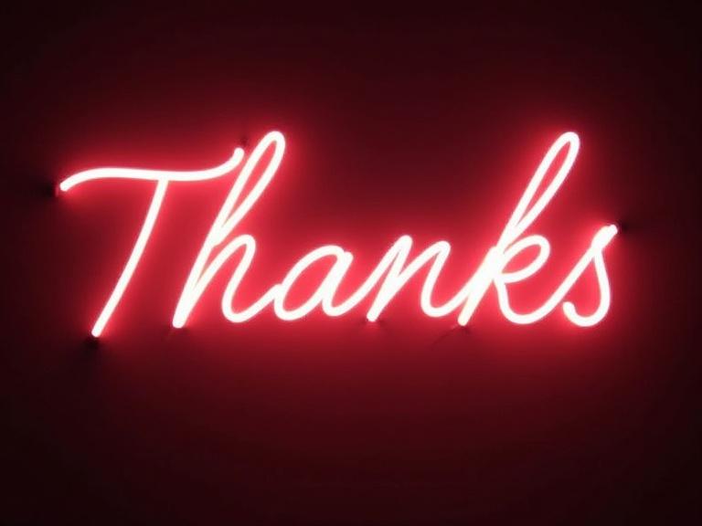 Neon light painting showing the word 'Thanks' in a cursive style. A voluptuous glow surrounding the text.