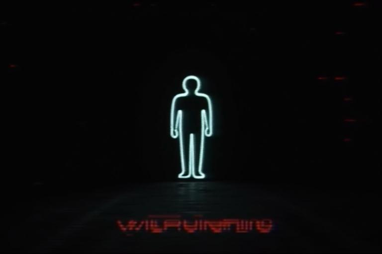 Analog horror warning screen featuring a minimalist person icon against a black background. The icon appears to be slowly pulled into the floor. The image includes VHS glitch effects, scanlines, and a retro CRT monitor aesthetic. The design is unsettling and evokes a creepy public service announcement feel.