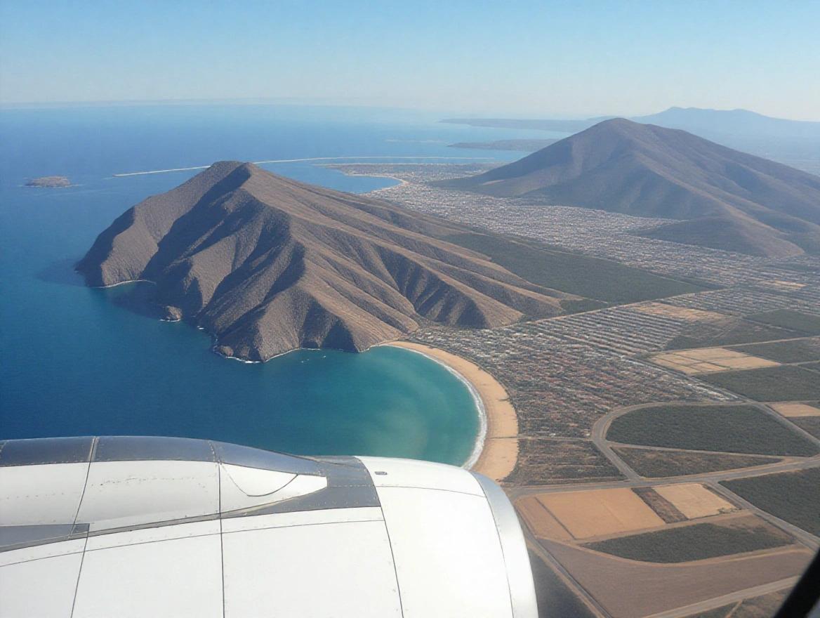 Aerial image capturing the Canary Islands from an airplane. The scenery includes mountains, a beach, and a clear blue sea. The aircraft wing is visible in the foreground.