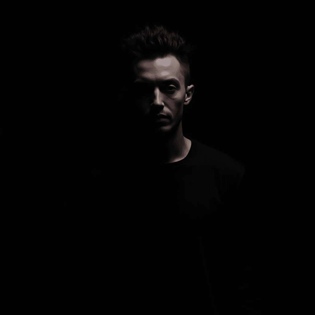 A person standing in a dark environment with partial lighting on the face.