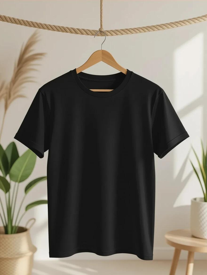 Plain black unisex T-shirt mockup hanging on wooden hanger in softly lit room. Room features boho decor and indoor plants. Background is neutral with warm cozy tones. T-shirt fabric appears smooth and realistic with empty front area and no artwork. Scene captures daylight from front.
